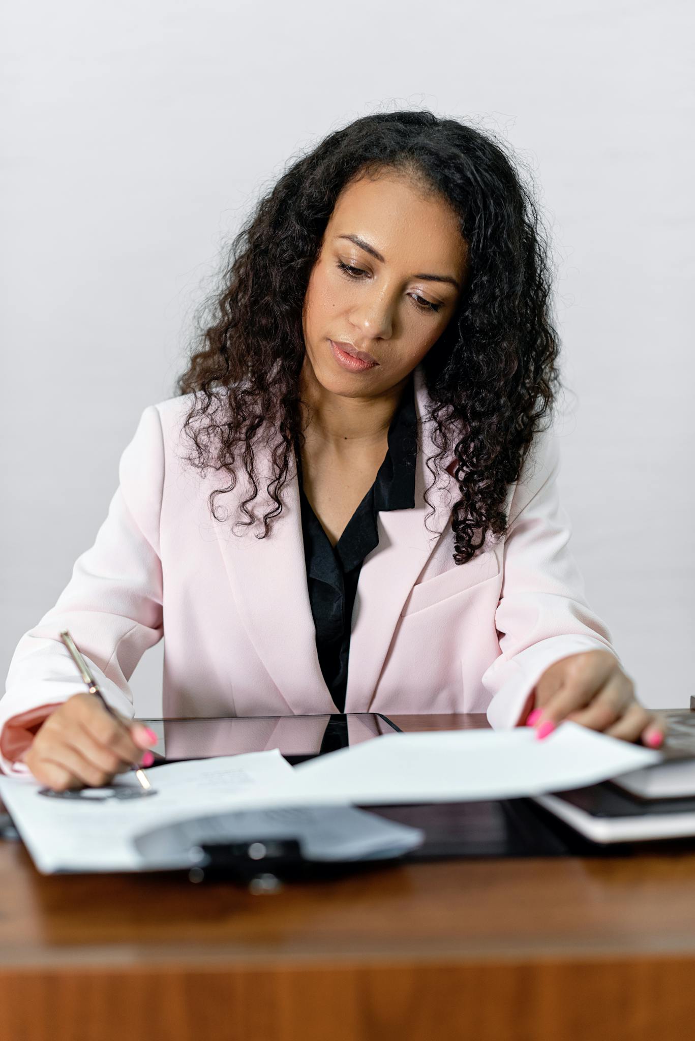Focused businesswoman signing important documents at her office desk.